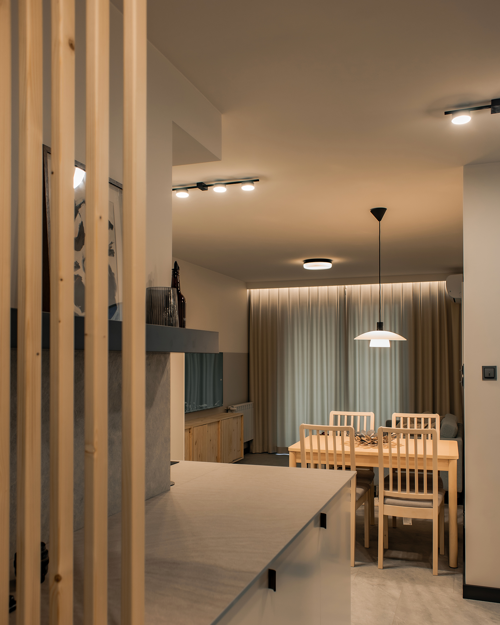 Zabudowa kuchenna płynnie przechodzi do korytarza. Drewniane lamelki nieco oddzielają od siebie te strefy.